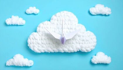 A paper origami bird soars from a fluffy, crocheted cloud surrounded by smaller clouds on a bright cyan background. Peaceful, simple, clean composition