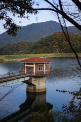There is a red-roofed house on a blue lake in the mountains.