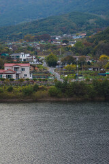Behind the clear lake, mountains and rural villages are visible.