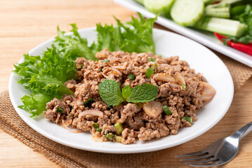 Local Thai food, Spicy minced pork salad (Larb Moo) eating with fresh vegetables on wooden background