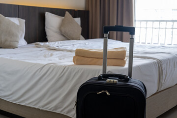 Traveler’s luggage placed beside bed in cozy hotel room symbolizing vacation and relaxation stay