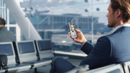 Businessman Does Video Call With a Client Using Animated Avatar on Smartphone at Airport. Advanced Connectivity Technology Keeps Global World Interconnected on Social Media