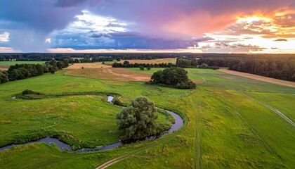 Winding River Through Pastoral Fields Under a Dramatic Sunset and Stormy Sky