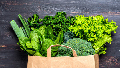 Fresh green vegetables in paper bag on dark wood fresh produce healthy eating