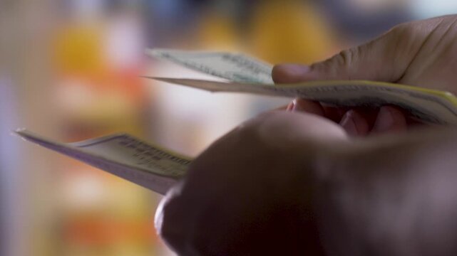 Person's hands hold, count and check validity of 100 dollar bills thoroughly. Close-up. Blurred background. Banking concept