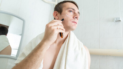 Handsome man shaving in the bathroom.