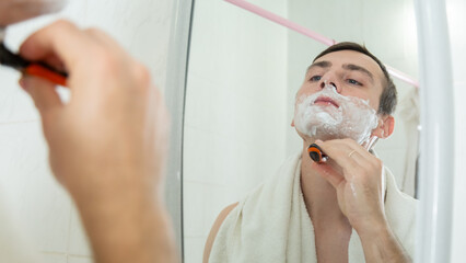 Handsome man shaving in the bathroom.