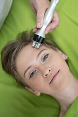 Naklejka na ściany i meble Top view of Caucasian woman undergoing radio wave RF lifting procedure in beauty salon. 