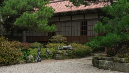 Serene traditional garden with lush greenery, ornamental stones, and wooden architecture