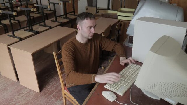 Man Sits In Front Of Old-fashioned Computer In Office 1980S, 1990S. Man Typing On Vintage Computer
