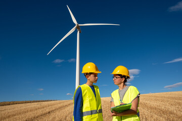 Renewable energy engineer is providing vocational training to a student in a wind turbine area,...