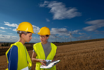 Renewable energy engineer is providing vocational training to a student in a wind turbine area,...