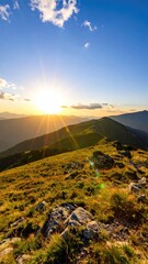A sunburst emanates over a mountain ridgeline, casting long shadows on rolling hills covered in golden grass under a bright blue sky with wispy clouds