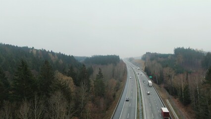 Aerial view of cars driving on remote highway among trees in mist