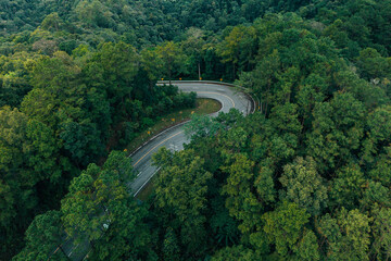 Aerial view of a road in the middle of a green forest in the rainy season. Environment and travel.