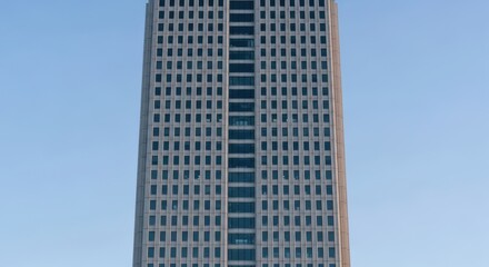 Obraz premium Modern skyscraper against blue sky with symmetrical windows