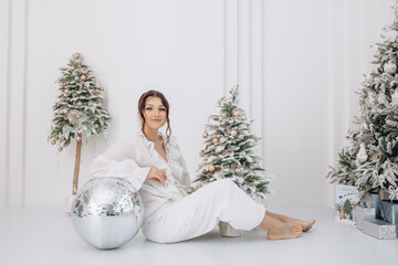 Beautiful fashionable brunette model woman in white jeans and blouse at Christmas