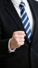 Close-up of a person in a suit making a fist, symbolizing determination or strength.