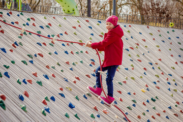 Happy child climbing on artificial rock wall on playground © Tatiana Foxy