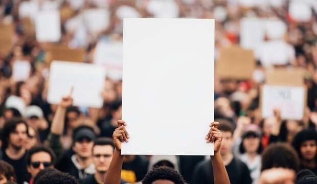 A person in a large crowd of protestors holds up a blank white sign, providing a powerful mockup for a social or political message.