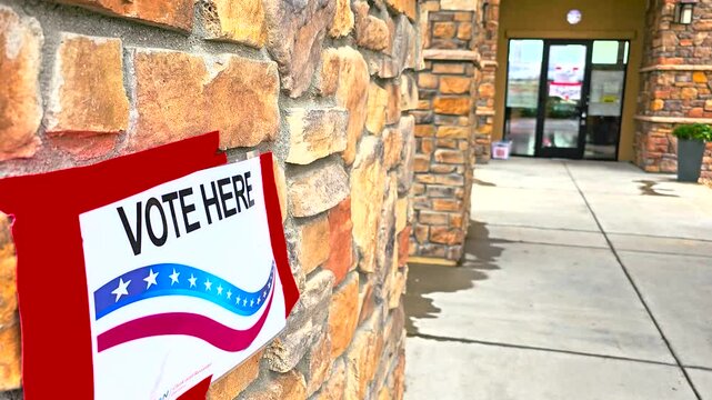 Vote Here sign shown in a close-up view with crisp focus, emphasizing its bold lettering. Great for stock footage on voting rights, election day, democracy, and civic engagement themes.