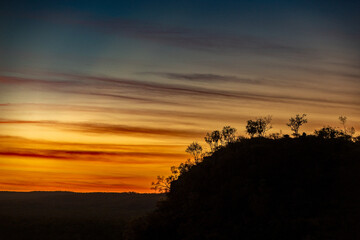 Sunset with a mountain and silhouetted trees.