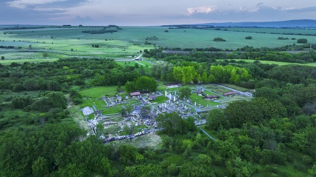 Drone orbit over Nicopolis ad Istrum as the ancient Roman city remains lie in shadow beneath a moody sunset sky