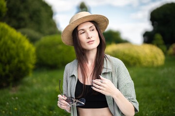 Woman enjoying a sunny day in a green park wearing a stylish hat