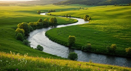Obraz premium Winding river through lush green hills at sunset