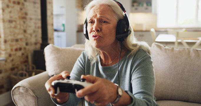 Senior woman, console and playing video games with headphones on sofa for online entertainment. Pensioner, elderly gamer or female person with controller or headset for online competition in house