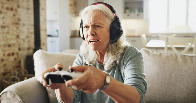 Senior, angry woman and playing with video games on sofa for competitive action or esport in home. Elderly, female person or gamer with anger, controller or headphones for online competition in house - Powered by Adobe