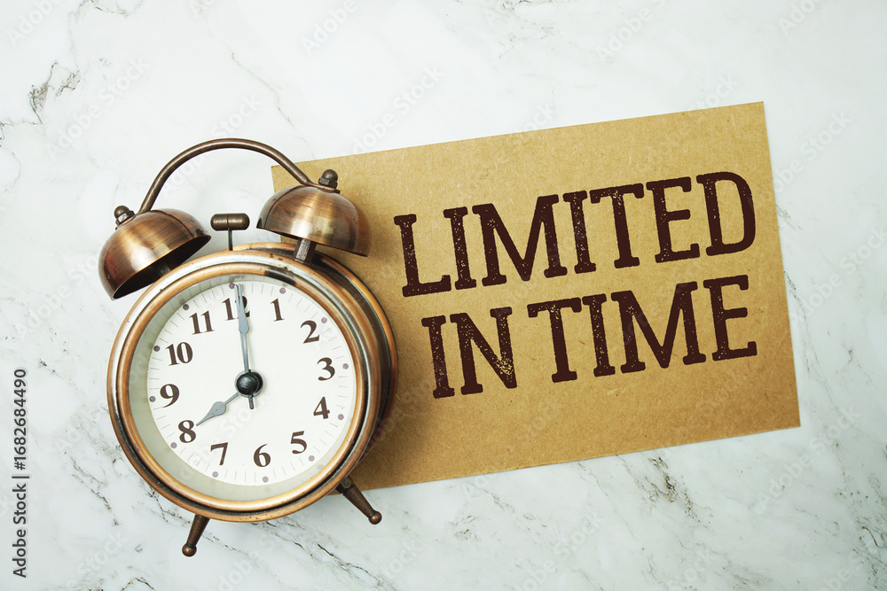Poster limited in time text written on paper card with alarm clock on marble background
