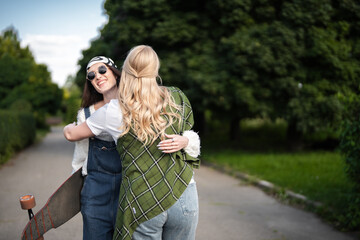 Friends joyfully reunite in a sunlit park during a warm afternoon