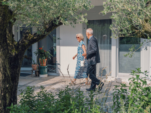 Married couple walking together outside their home on a summer day