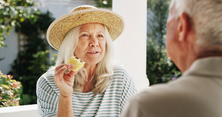 Patio, old couple and bonding with fruit, home or conversation on weekend, wellness or healthy food. Outdoor, senior woman and elderly man with pineapple on break, romance and people with commitment