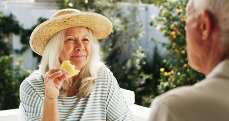 Patio, old couple and talking with fruit, home or conversation on weekend, wellness or healthy food. Outdoor, senior woman and elderly man with pineapple on break, romance and people with commitment