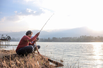 Fishermen are Squatting on the Lakeshore, Casting their Fishing Rods into the Calm Water