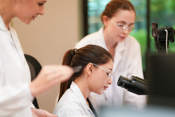 A senior pathologist supervises a junior researcher during histopathological analysis. The team...