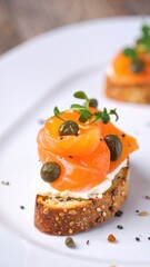 Open-faced appetizer with smoked salmon, cream cheese, capers, and microgreens on crusty bread, elegantly presented on a white plate