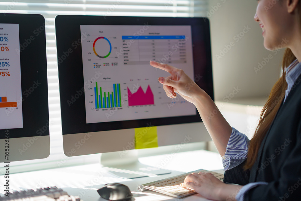 Poster businesswoman pointing at computer screen showing financial charts and graphs, analyzing data for bu