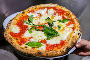 Pizza Margherita tradizionale napoletana con sugo di pomodoro, mozzarella di bufala e basilico fresco appena sfornata in una pizzeria