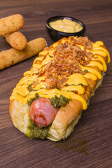 Panino da hot dog ripieno di hot dog artigianale e guarnito con salsa ai friarielli, senape e bacon croccante, servito in un pub con contorno di mozzarella filante fritta