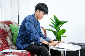 Serious Male Student Or Freelancer Works From Home With Coffee Cup And Documents On Table