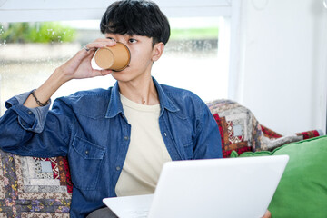 Freelancer Young Asian Man Drinks Coffee On Cup While Working From Home