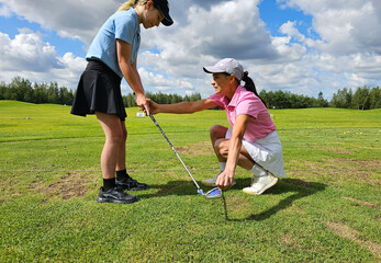 Coach demonstrates proper golf techniques to young student