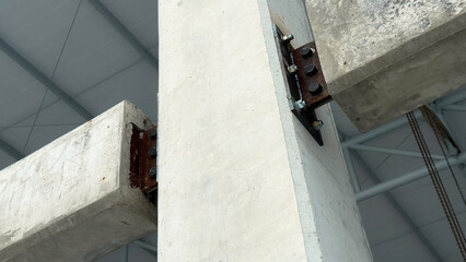 Structural connection of concrete beams to a column with steel plate and bolts, showing engineering details in construction framework.
