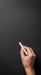 Hand holding white chalk against a dark textured chalkboard blackboard writing