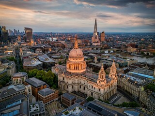 Aerial sunset view of the skyline of London, England, with St. Pauls Cathedral, river Thames and Tower Bridge in soft sunlight