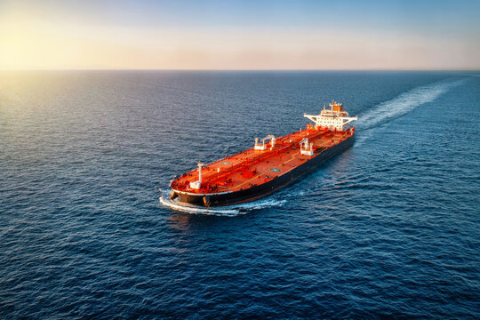 Aerial view of a heavy loaded crude oil tanker traveling over open ocean during sunset time
