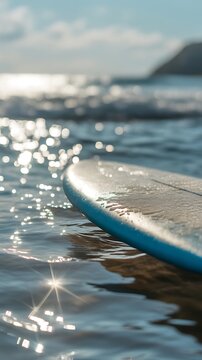 Close-up of surfboard resting on shimmering ocean water in a serene summer scene